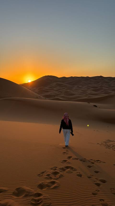       Solo traveler in a desert landscape with sand dunes at sunset.
  