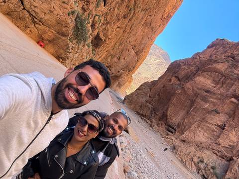       Three people excitedly posing in a rocky gorge.
  