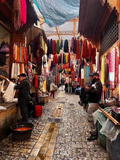       Colorful market with hanging textiles and cobblestone street
  
