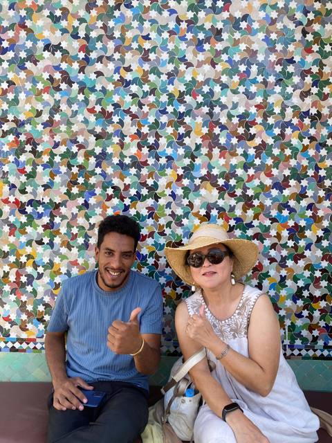 Two people relaxing against a colorful tiled wall.