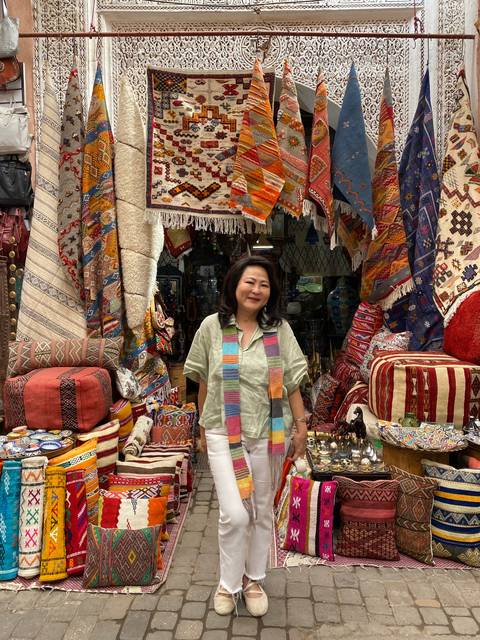       Person standing in front of a colorful textile shop.
  