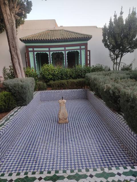       A view of a courtyard with detailed tile work and plants in an ornate setting.
  