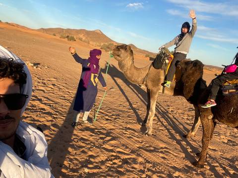       People riding camels in the desert.
  