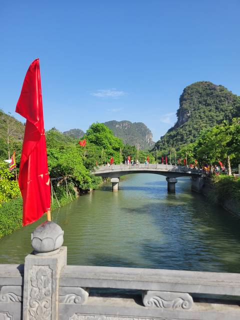 Bridge crossing a river surrounded by lush greenery and mountains.