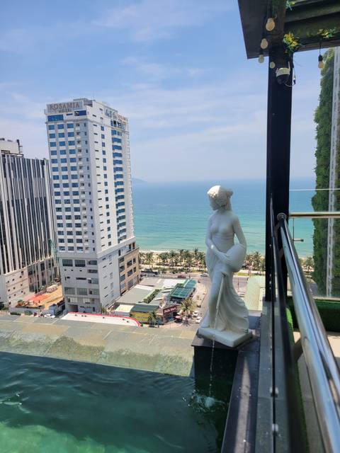 Statue overlooking a beachfront with buildings and sea.