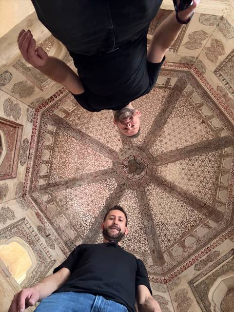 Two men standing inside an ornately decorated dome.