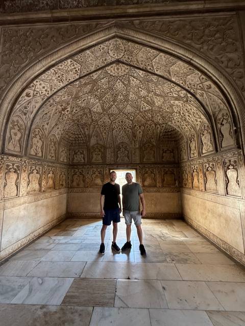 Two men in a decorative archway with intricate carvings.