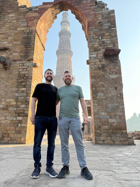 Two people standing under an arch with a monument in the background.