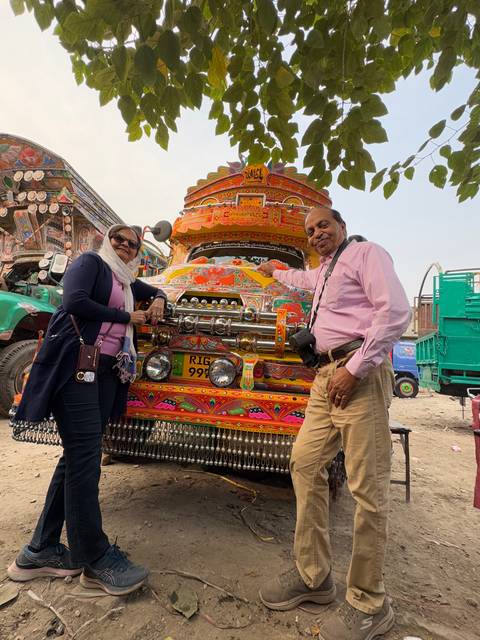       Two people posing with a colorful decorated truck.
  