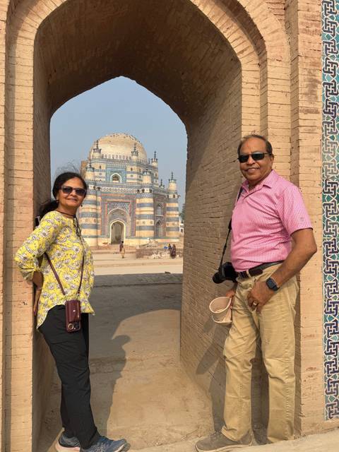       Couple posing near a historic mosque with blue and white tiles.
  