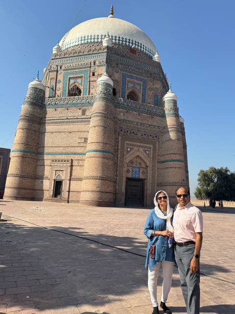      Couple standing in front of a large historic tomb.
  