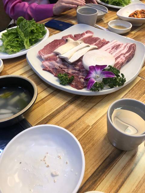 Close-up of a plate with uncooked meat and vegetables on a table.