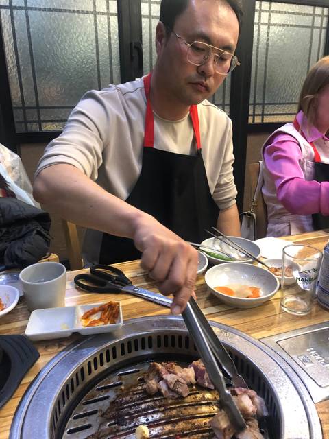 A man grilling food at a table with dishes around.