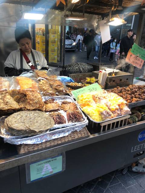 A busy street market with food stalls displaying various foods.