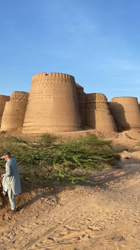 Person standing in front of ancient fort in a desert landscape