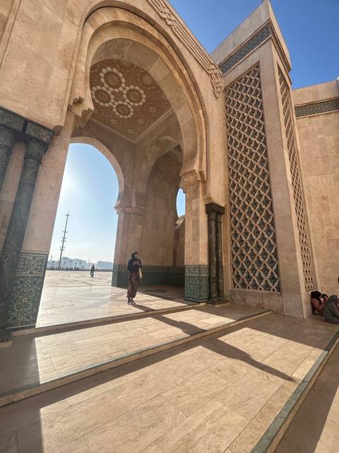 Man walking through archways of a Moroccan mosque.