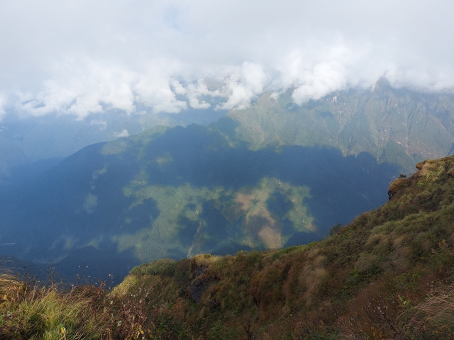 Mountain range with clouds and grassy slopes.