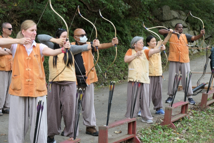 Group of people practicing archery outdoors.
