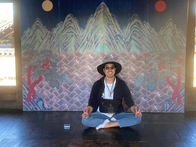 Person sitting cross-legged in front of a colorful mural.