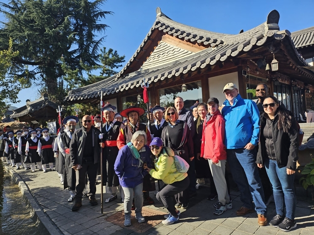 Group of people in traditional Korean attire posing in front of a hanok-style building.
