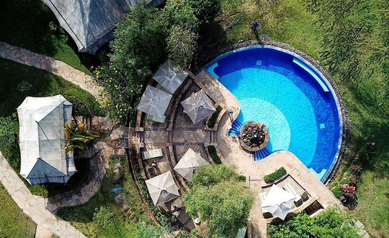       Aerial view of a pool and surrounding area at a resort.
  