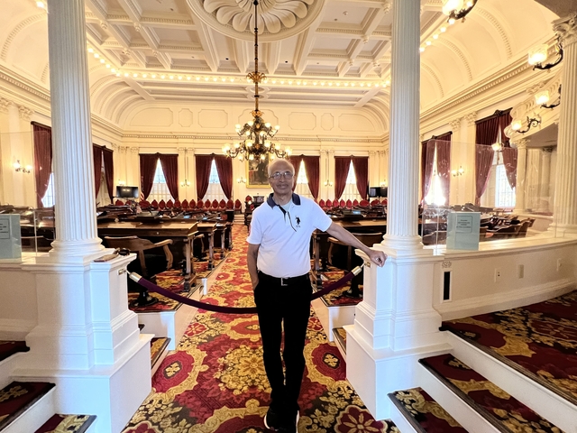       Man standing inside an ornately decorated building with chandeliers.
  