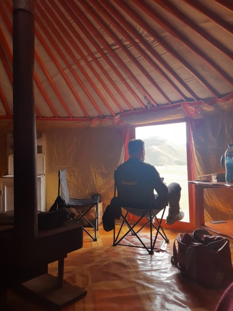       Person sitting inside a ger looking out at the landscape.
  