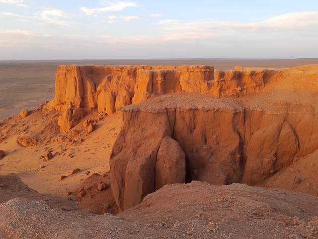       Orange cliffs in a desert landscape at sunset.
  
