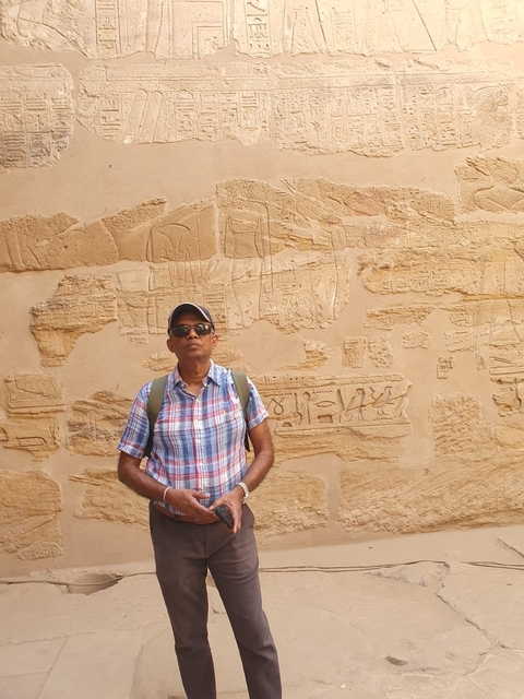 Person standing near ancient Egyptian hieroglyphic reliefs.