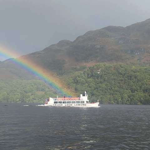 Boat on a lake beneath a vibrant rainbow.