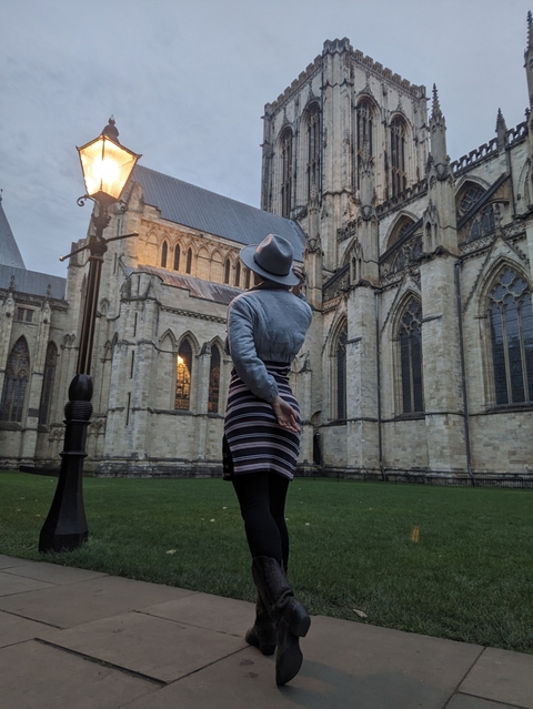 Person in a hat standing before a large cathedral.
