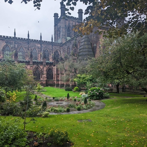 Historic red brick cathedral within a garden courtyard.