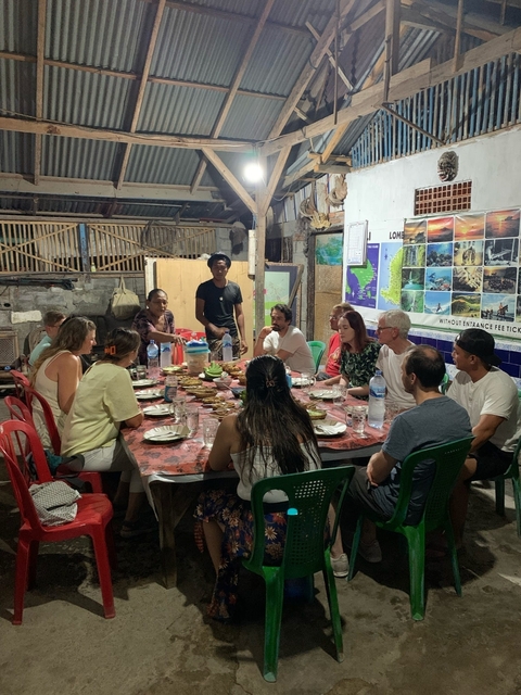 Large group of people gathered around a table, having a meal.