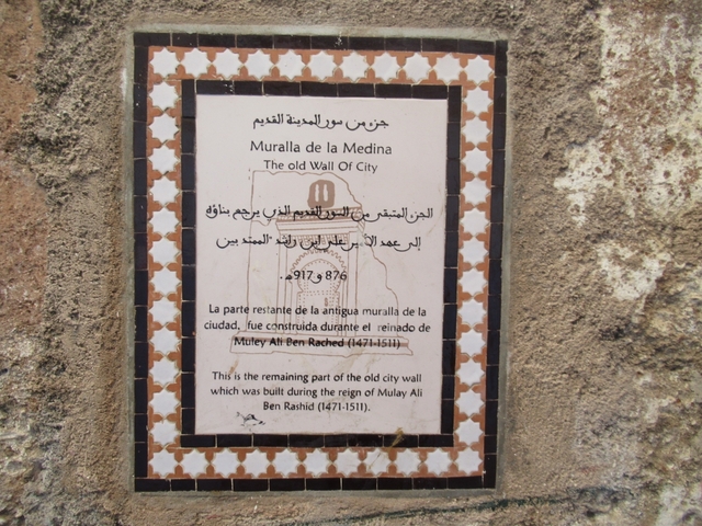       Historical plaque on a textured wall with Arabic and Spanish text.
  