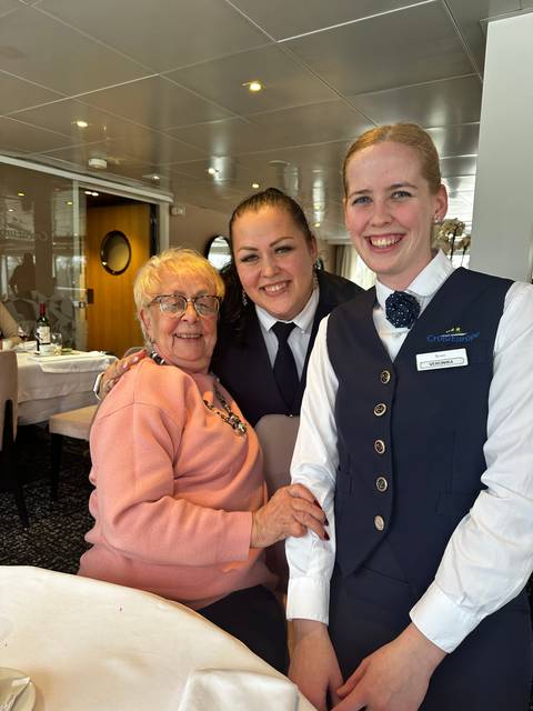 Two people posing with a woman in a restaurant.