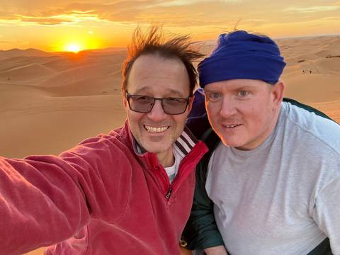 Two people upside down posing in front of a desert sunset.