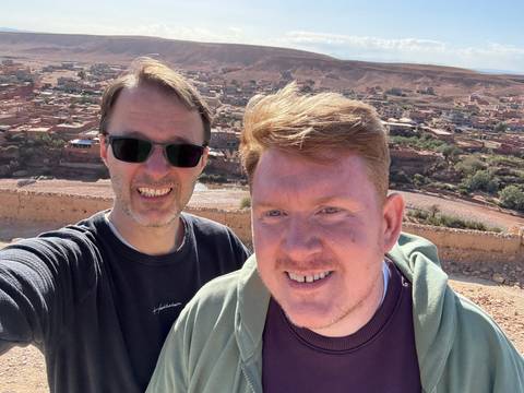 Two people posing for a photo with a landscape view.