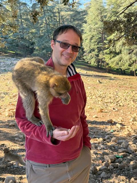 A man holding hands with a small monkey.