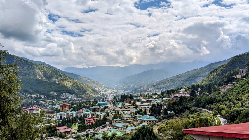       Panoramic view of a Bhutanese town with mountains.
  