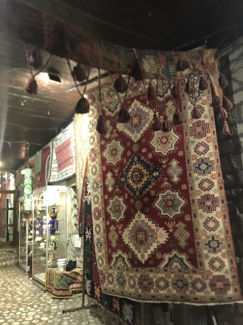 Display of traditional woven rugs in a market.