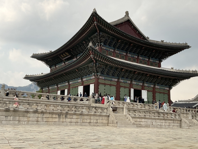       Large traditional Korean building with people walking.
  