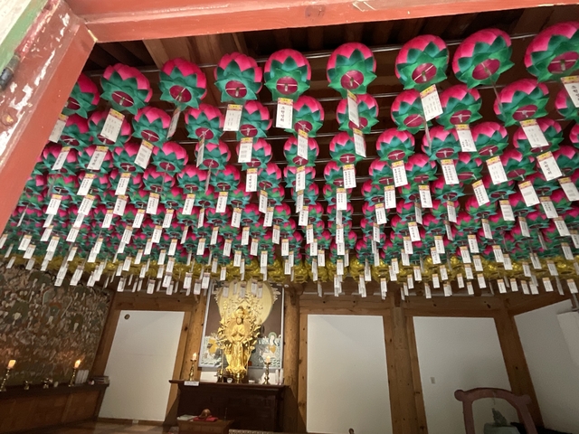       Indoor space with colorful ceiling decorations and a statue.
  