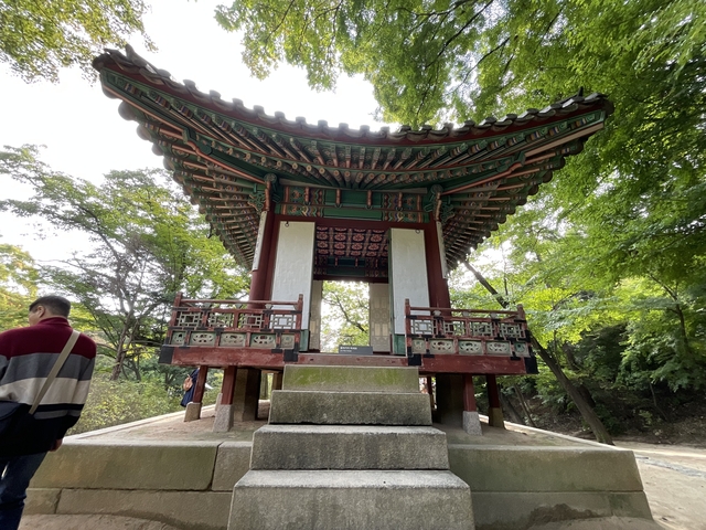       Traditional Korean pavilion in forest setting.
  