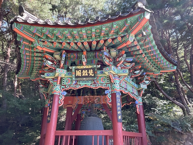       Colorful Korean temple with foliage behind.
  