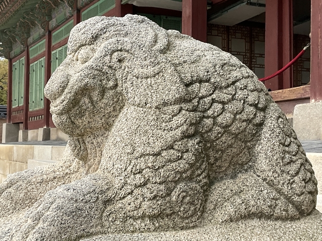       Stone lion statue in front of a traditional building.
  