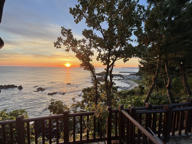       Sunset over the ocean with rocky shoreline.
  