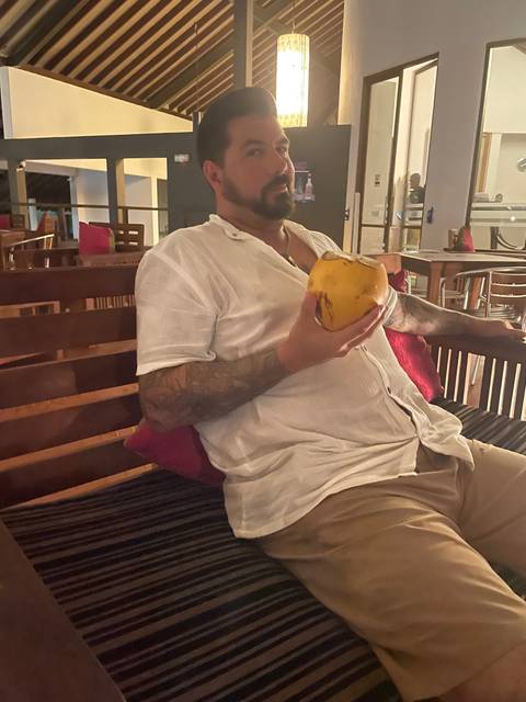 Person reclining indoors while holding a coconut.