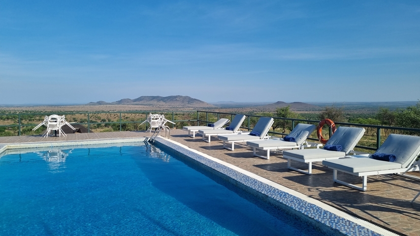 Swimming pool with loungers overlooking a scenic landscape.