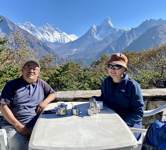 Two people enjoying a tea with a mountainous view.