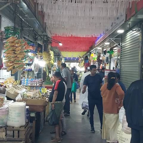       Indoor market with people shopping, colorful decorations.
  